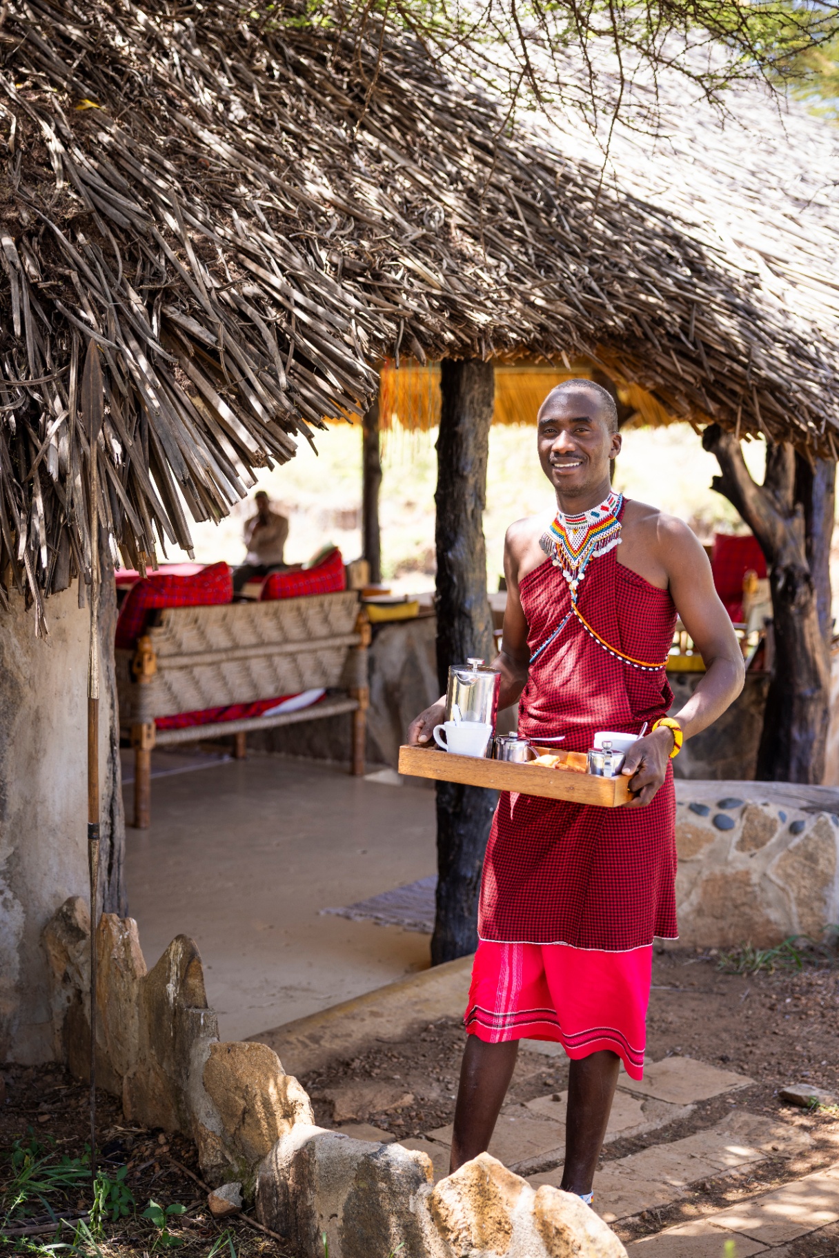 Maasai front of house team member carrying a tea tray at the lodge entrance